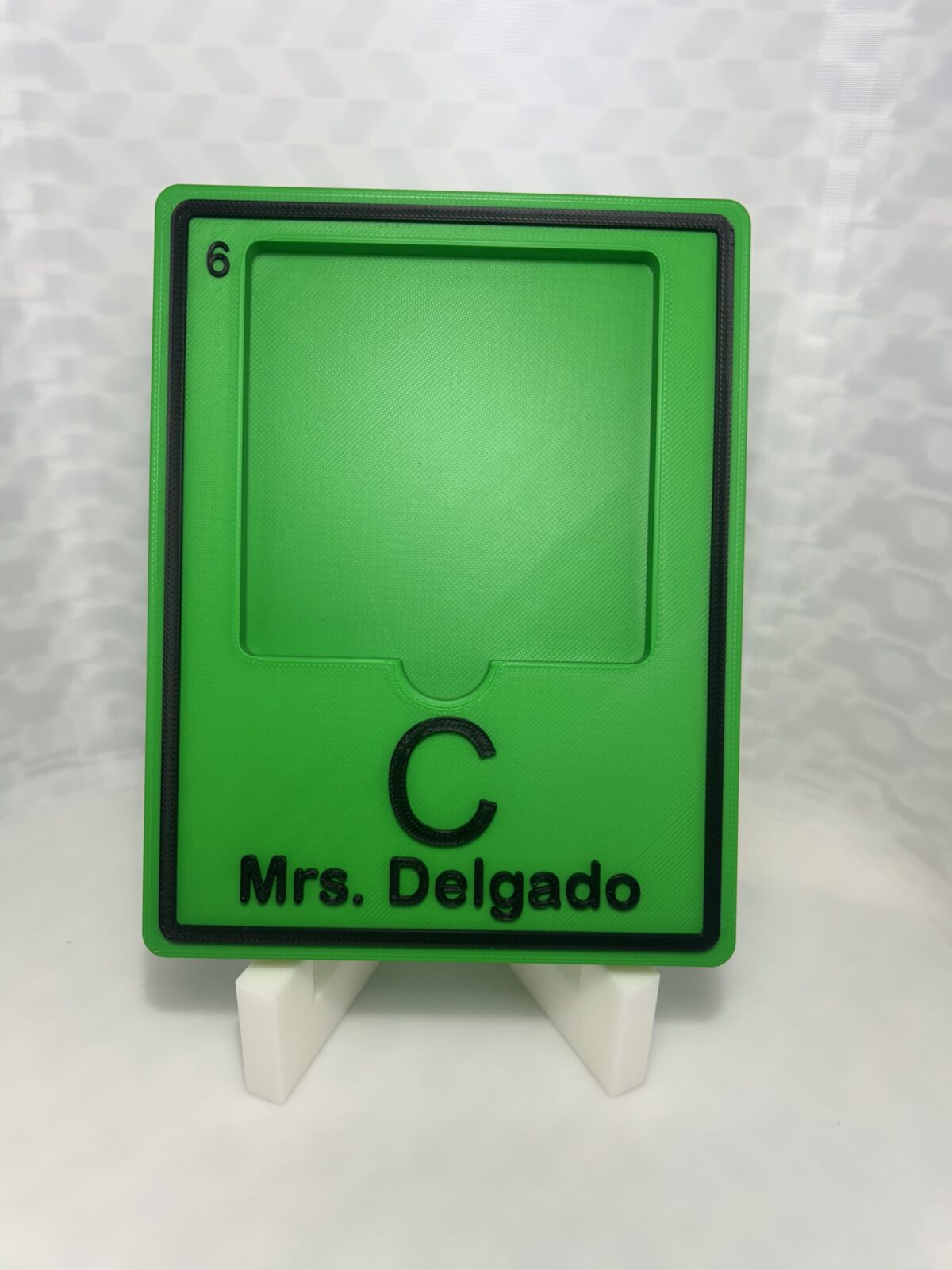 Green 3D printed periodic table element tile holding a sticky note pad, with the element symbol and a teacher name