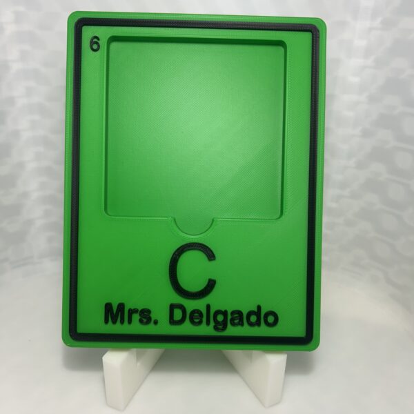 Green 3D printed periodic table element tile holding a sticky note pad, with the element symbol and a teacher name