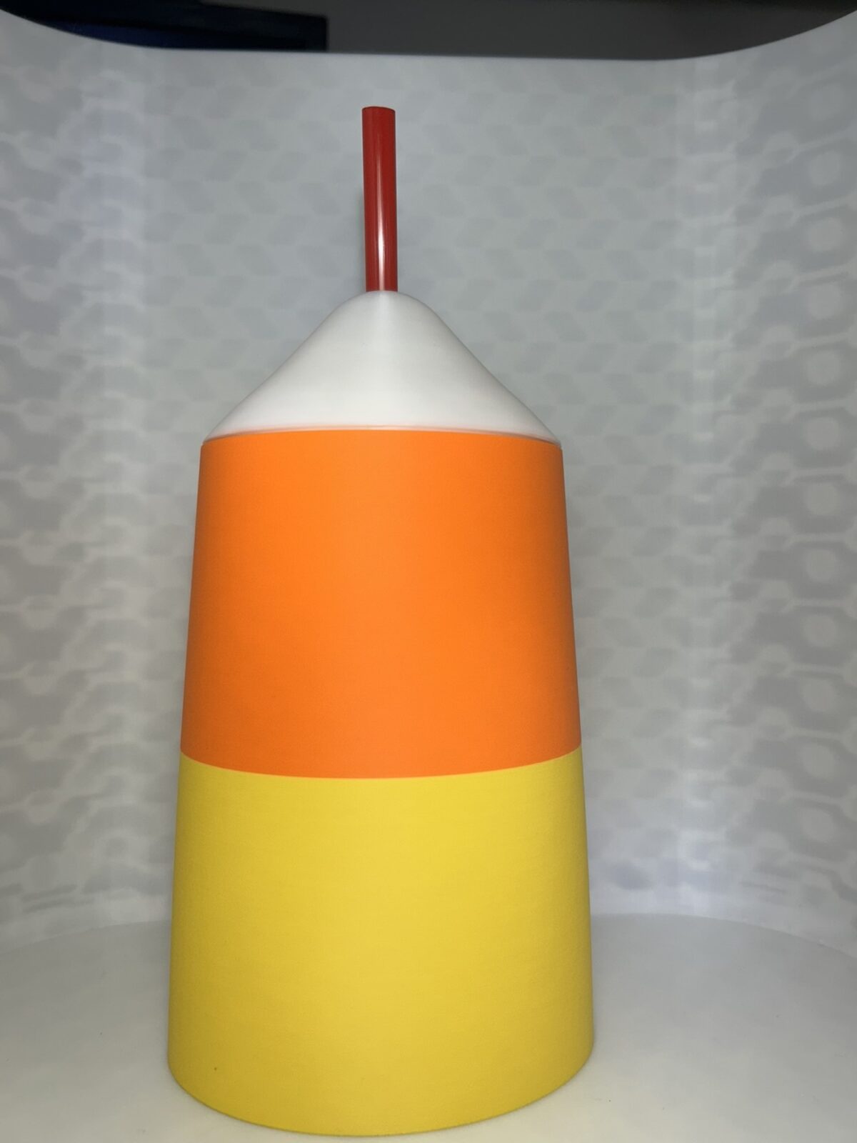 Candy corn drink can cover in yellow, orange and white with a straw
