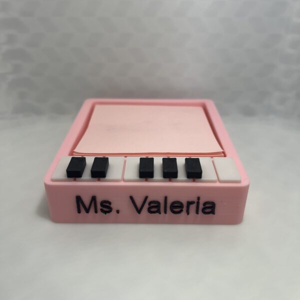 Pink 3D printed piano sticky note holder with black and white keys and the name Ms. Valeria