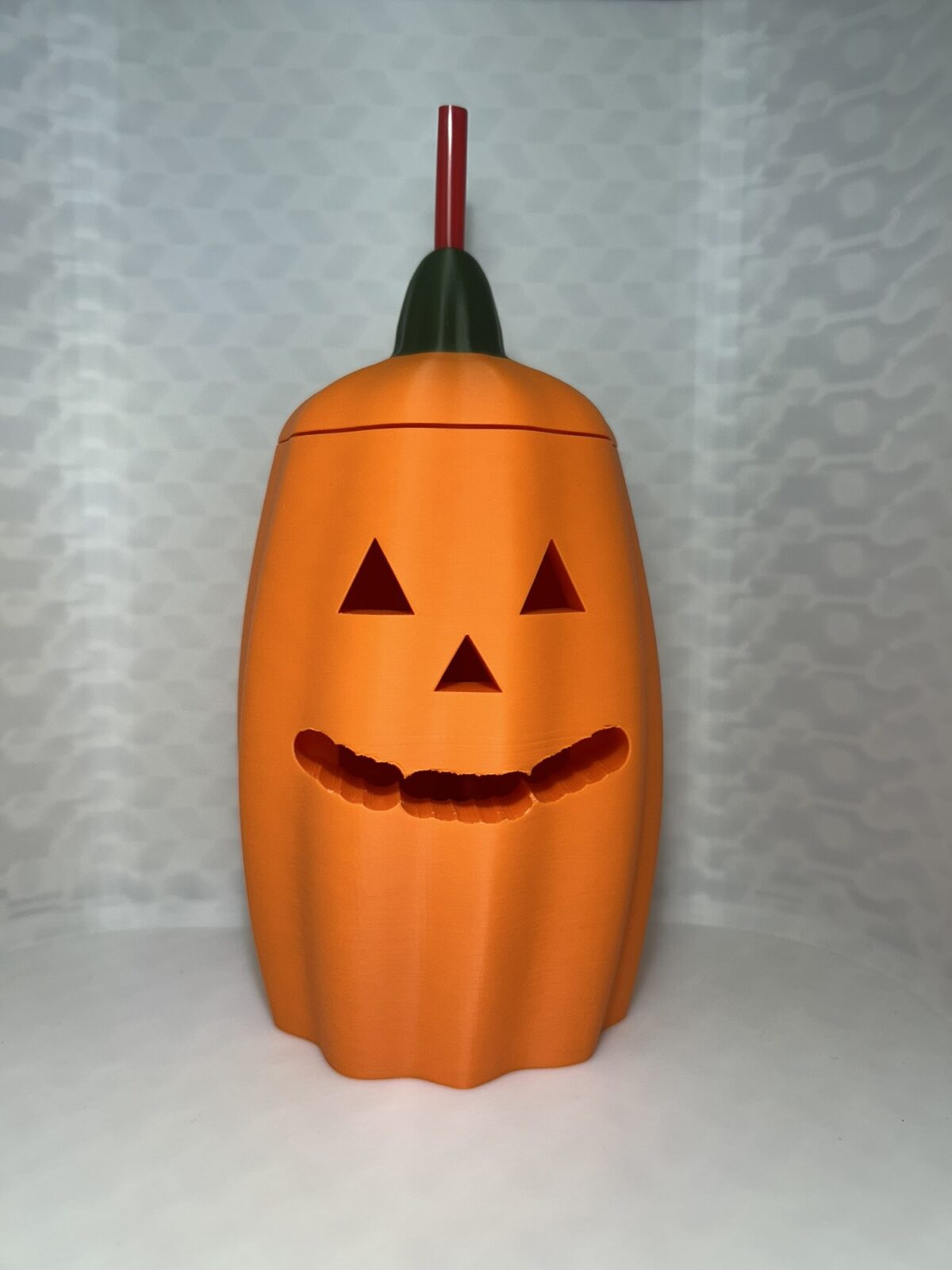 Orange jack-o-lantern drink can cover with green stem lid and a straw
