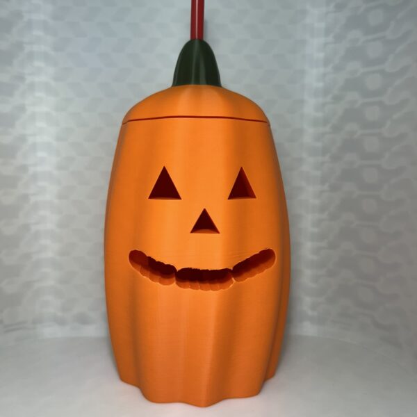 Orange jack-o-lantern drink can cover with green stem lid and a straw
